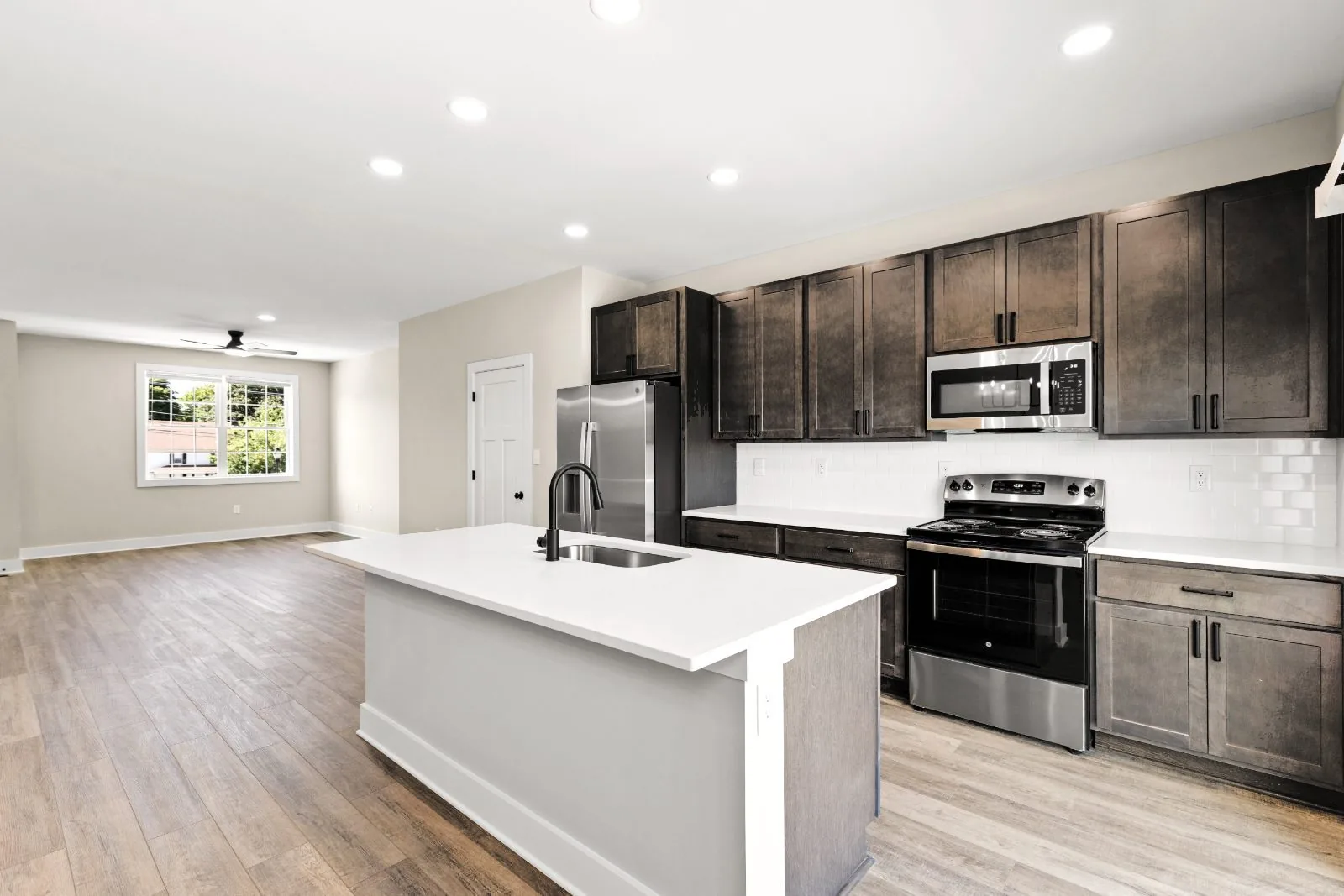 Kitchen with quartz island and subway tile, open to the living area